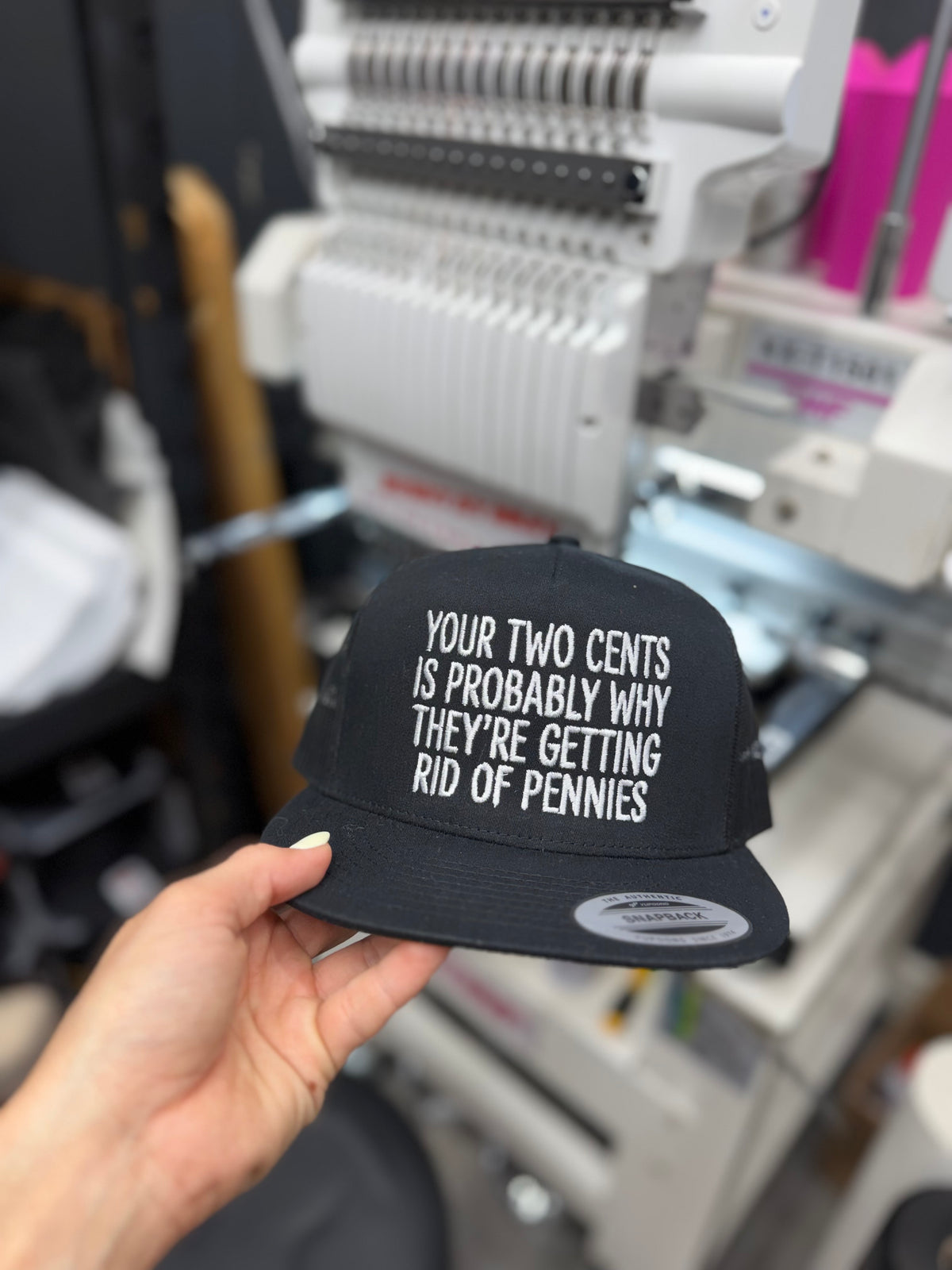 a hand holding a black hat with white text